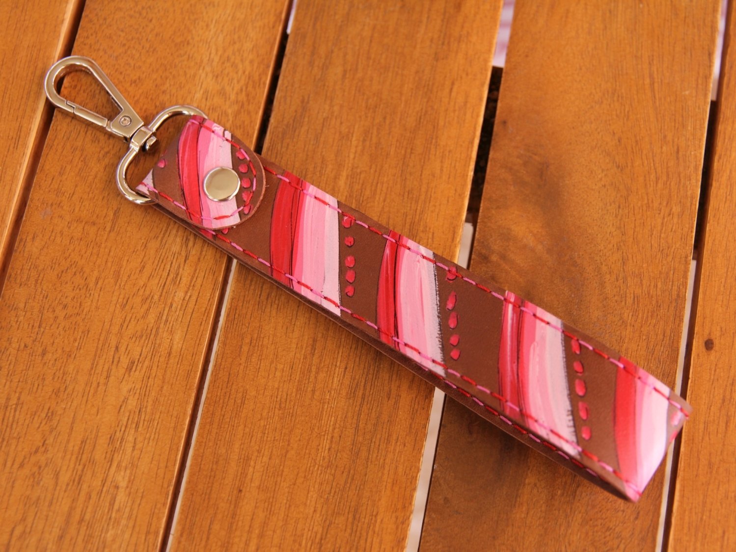 Schlüsselhalter aus Nubukleder in mittelbraun, bemalt mit Streifen in rot rosa weiß, Garnfarbe in rot und pink