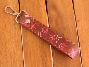 Schlüsselhalter aus Leder in mittelbraun, bemalt mit bunten Symbolen in rot und rosa, Garnfarbe in rot und pink