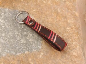 Kurzer Schlüsselanhänger mit Ring, die Garnfarbe ist in rot und orange, mit bunten Streifen